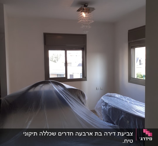חדר עם רהיטים מכוסים בניילון לקראת צביעה
